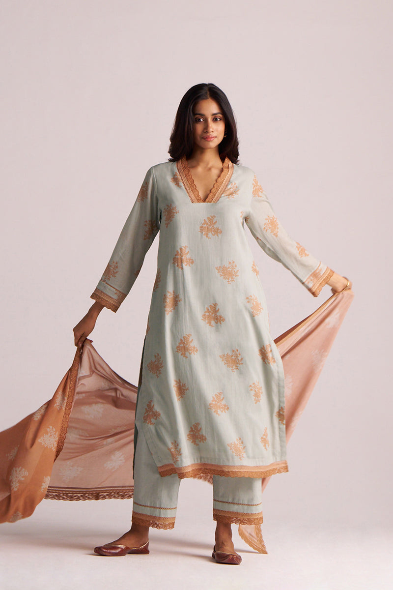 Woman wearing a Grey-Rust Mul Kurta Set with floral patterns on a plain background