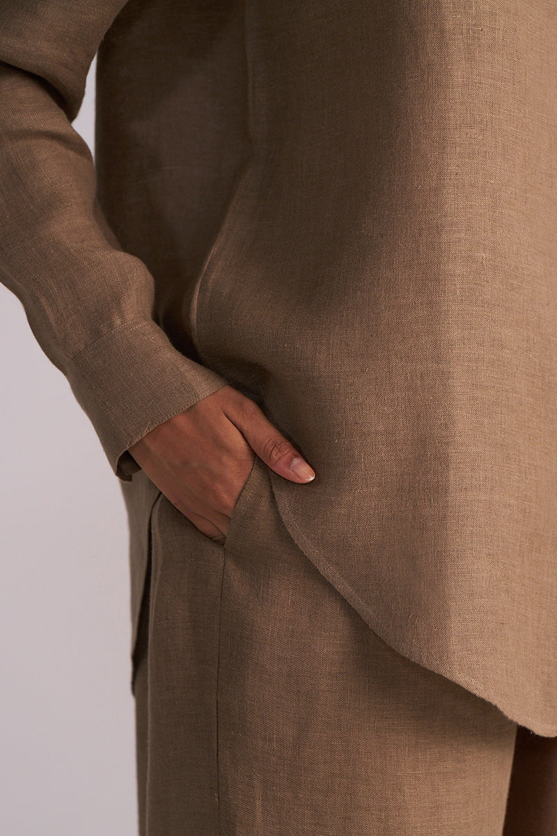 Woodsmoke Brown Pure Linen Co-ord Set with a hand in the pocket on a light gray background